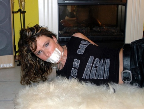 Clothed girl struggles against a gag while hogtied on a rug 56130374